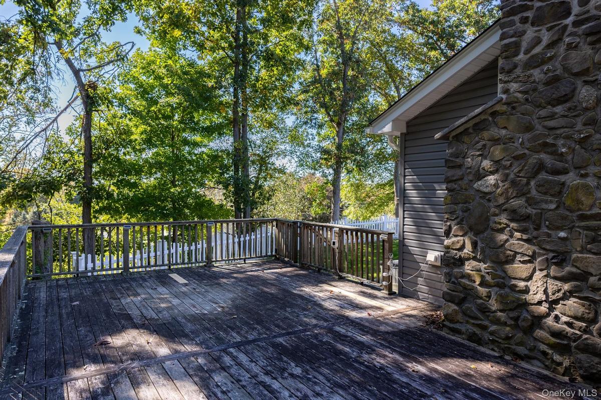 Additional view of the home's exterior deck and tree lined surroundings.