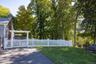 View of the open lawn bordered by fencing and mature trees.