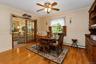 Breakfast nook hardwood flooring, paneled wainscoting, glass-paneled sliding doors, window with interior shutters, and a ceiling fan with integrated l