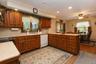 Kitchen featuring wood cabinetry with pullout shelving, solid surface countertops, recessed lighting, and a dining area with a ceiling fan