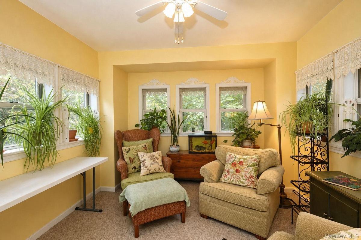 Garden room with recessed wall detail, three transom windows, ceiling fan with light fixture, carpeted flooring