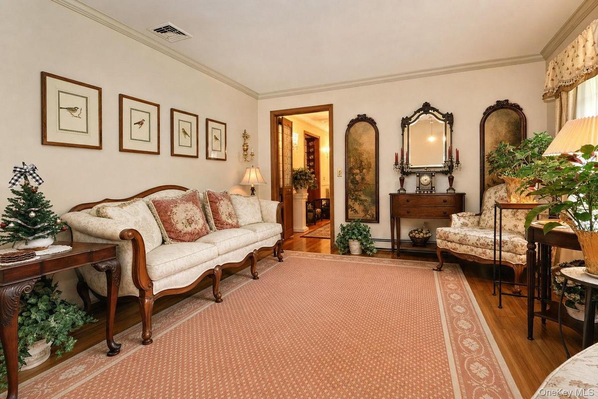 Hardwood flooring, crown molding, and a decorative area rug define this inviting space