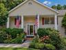 Cream-colored siding exterior with a covered porch, featuring decorative pillars and red window shutters