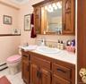 Wood-finish vanity with ample storage, integrated countertop, and an oval basin