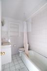 Bathroom featuring a white vanity with a porcelain sink, a toilet, and a bathtub with tile surround