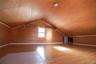 Spacious attic room with vaulted ceiling, wood-finish flooring, and abundant natural light from dormer window