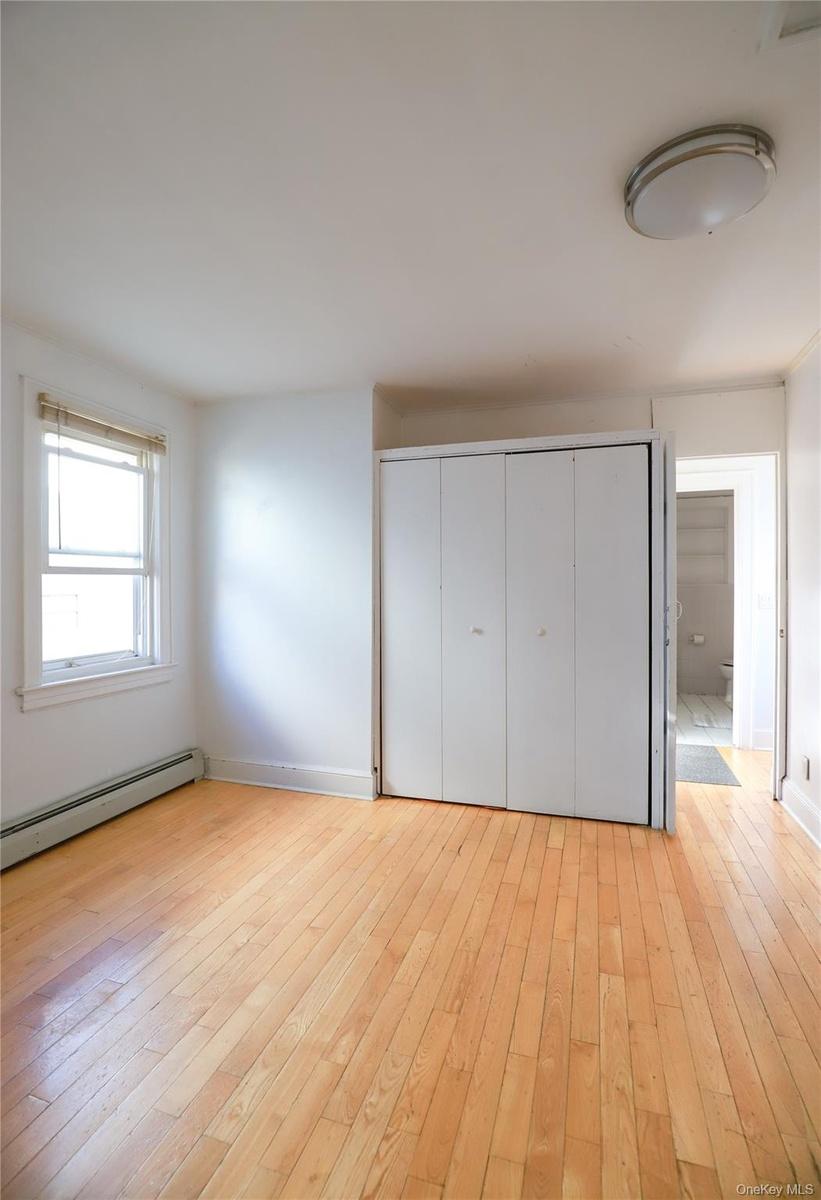 Bright bedroom featuring hardwood flooring, large closet with bifold doors, and abundant natural light from a sizable window