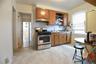 Bright, open kitchen featuring wood-finish cabinetry, stainless steel appliances including a gas range, white countertops, and abundant natural light 