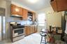 Kitchen featuring wood-finish cabinetry, stainless steel gas range, and white tiled backsplash