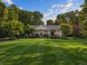 Expansive front lawn with mature trees and established landscaping