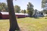 Additional view of the barn and residence highlighting the tree-lined grounds.