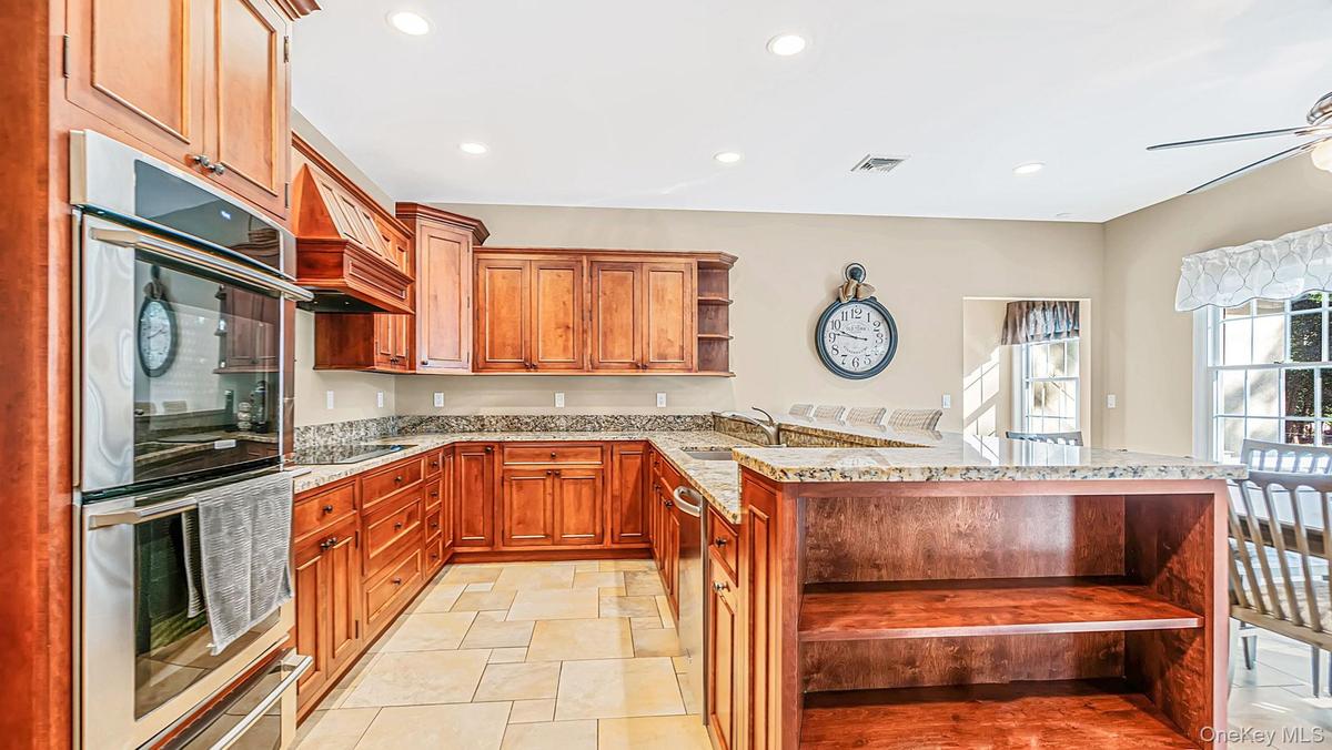 Kitchen featuring wood cabinetry, stone countertops, stainless steel appliances, and a breakfast bar