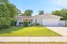 A welcoming first impression with a broad front lawn, mature landscaping, and a tile roof that adds distinctive Florida character.
