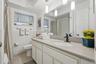 A generous vanity, broad mirror, and pendant lighting create a bright, comfortable space to get ready, with cabinet storage below.