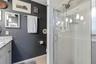 The primary bath features a glass-enclosed shower with classic white tile, glass corner shelves, and a convenient handheld showerhead.