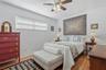 A welcoming second bedroom with soft neutral tones, warm wood-look flooring, and a wide window offers an inviting place to settle in.