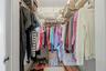 Keep your wardrobe within easy reach in a walk-in closet featuring hanging space on three sides and overhead shelving for extra storage.