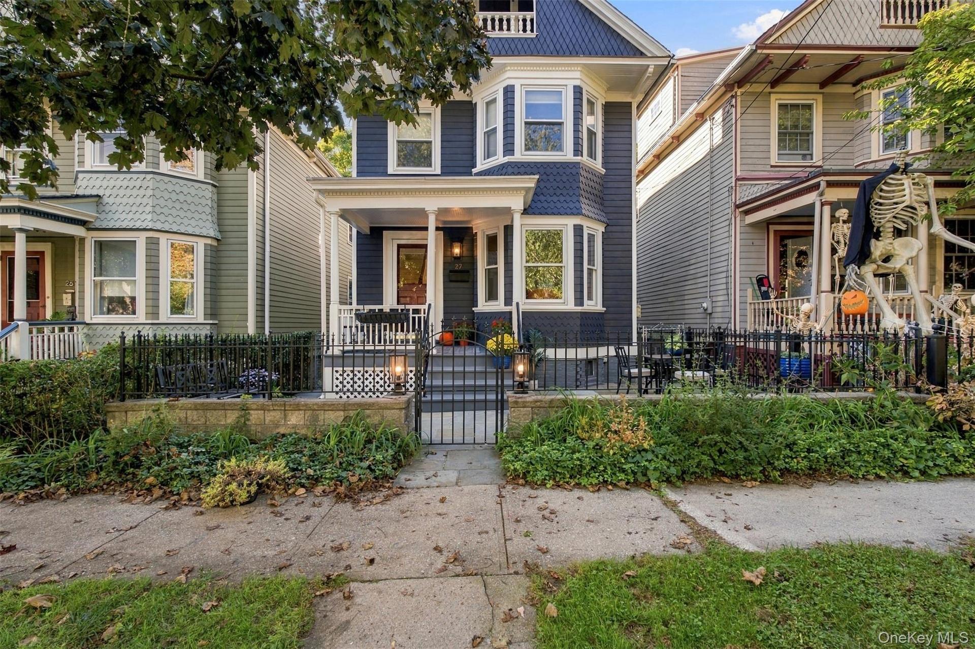 Two-story dark blue siding exterior with bay windows