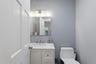 White vanity with an integrated sink and brushed nickel faucet, illuminated by a vanity light fixture over a rectangular mirror
