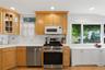 Kitchen featuring wood-finish cabinetry, white countertops, a stainless steel gas range, a built-in microwave, and recessed lighting