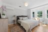Hardwood flooring, bay windows, crown molding, white ceiling fan, and wall-mounted air conditioning unit