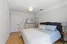 Wood-finish flooring, white walls, white trim, dual white paneled doors, and a decorative ceiling light fixture