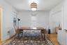 Hardwood flooring paired with white walls, decorative crown molding, and a drum pendant light fixture