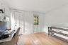 Hardwood flooring, white walls, crown molding, white doors with black hardware, and a window with blinds