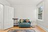 Hardwood flooring, crown molding, white interior door, white window trim, and white baseboards