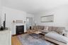 Hardwood flooring, crown molding, and a fireplace with a white mantel and dark stone surround