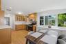 Hardwood flooring, light wood cabinetry, white countertops, built-in stainless steel appliances, and a wall of windows