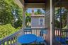 Covered balcony featuring white spindle railings, dark wood-finish ceiling, and shingle siding