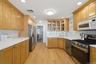 Hardwood flooring throughout, extensive wood cabinetry, white countertops, built-in stainless steel appliances, and recessed lighting
