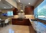 Kitchen with granite countertops, stainless steel appliances, wood cabinetry, tile flooring, and recessed lighting