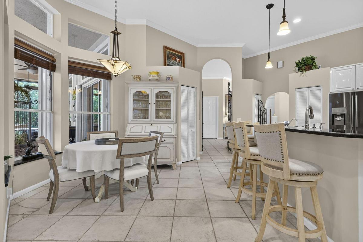 Open concept living space featuring tile flooring throughout, high ceilings, multiple arched doorways, and a kitchen with a dark countertop and white 