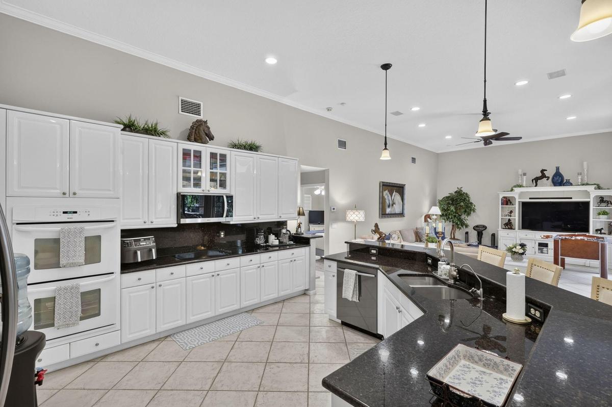 Kitchen featuring white cabinetry, dark stone countertops, stainless steel appliances, and tile flooring