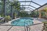 Screened enclosure with a freeform swimming pool, paver deck, and covered patio area