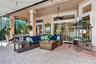 Covered outdoor patio with geometric paver flooring, multiple sliding glass doors, and a ceiling fan