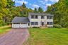 Two-story residence with a two-car garage, gravel driveway, and a welcoming front porch with wooden steps