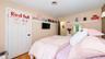 Light-toned wall paint, natural wood-finish flooring, white four-panel door with dark hardware, white wall-mounted shelving