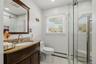 Dark wood-finish vanity with a granite countertop, undermount sink, and chrome faucet