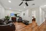 Spacious living room showcasing warm wood-finish flooring, recessed ceiling lighting, and a ceiling fan with integrated light fixture