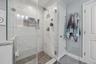 A seamless glass shower and a linen closet.