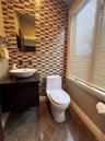 Mosaic tile accent wall, vessel sink, floating vanity with dark countertop, large window with blinds, and tiled flooring