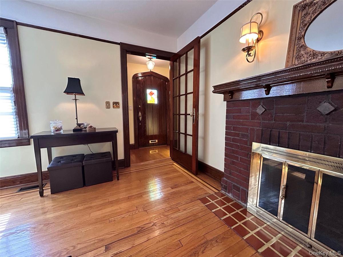 Wood-finish flooring, brick fireplace with decorative tile hearth, ornate wood mantel, glass-paneled interior door, and solid wood entry door with sta