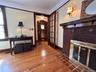 Wood-finish flooring, brick fireplace with decorative tile hearth, ornate wood mantel, glass-paneled interior door, and solid wood entry door with sta