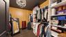 Walk-in closet featuring built-in shelving, hanging rods, an ornate chandelier, dark ceiling, and wood-paneled walls