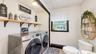 Laundry area featuring upper shelving, a window, and wood-finish flooring