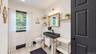 White interior walls with a black paneled door, light wood-finish flooring, and a modern black vanity with a vessel sink