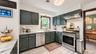 Kitchen featuring dark green cabinetry, light-toned countertops, white subway tile backsplash, stainless steel appliances, and wood-finish flooring